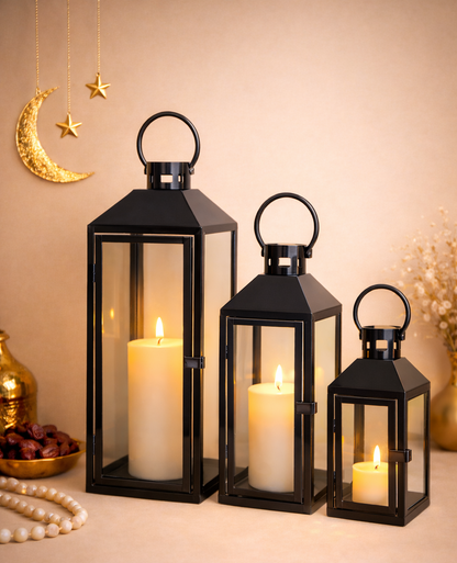 Three black lanterns with lit candles on a beige background, decorated with moon and star symbols.